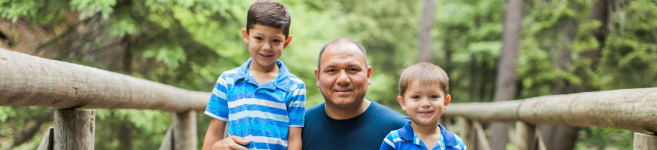Father walking with sons on a trail bridge