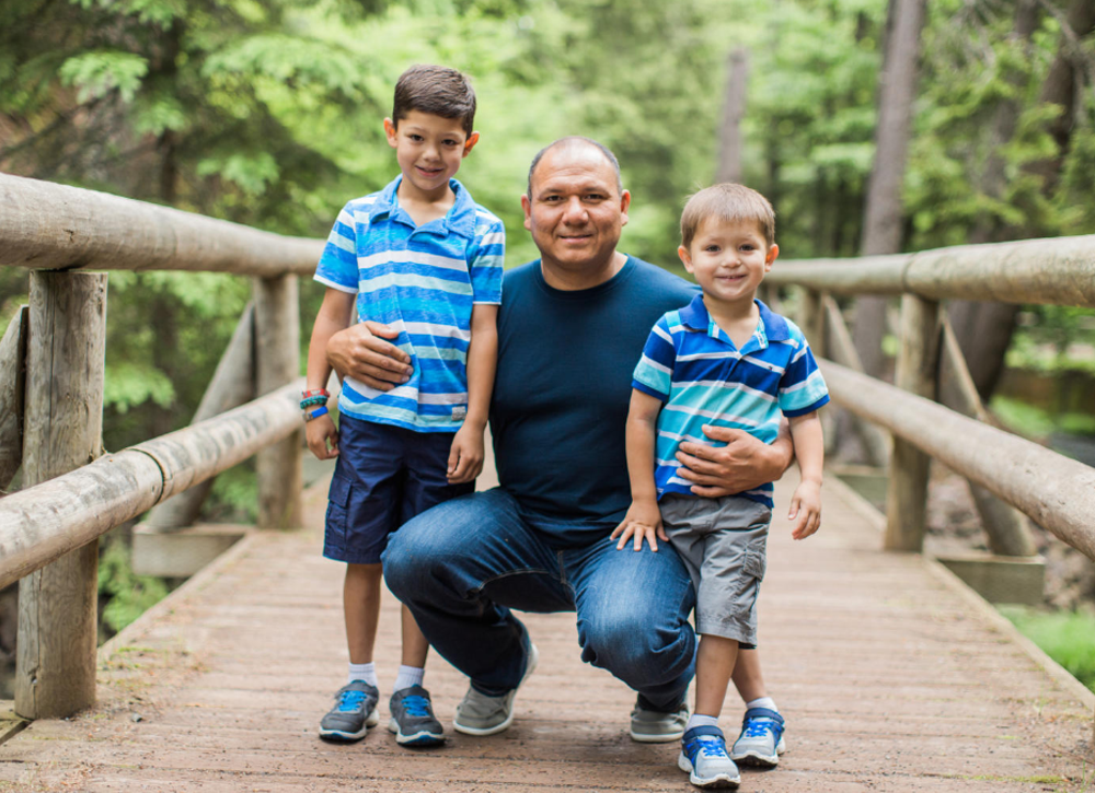 Father walking with sons on a trail bridge