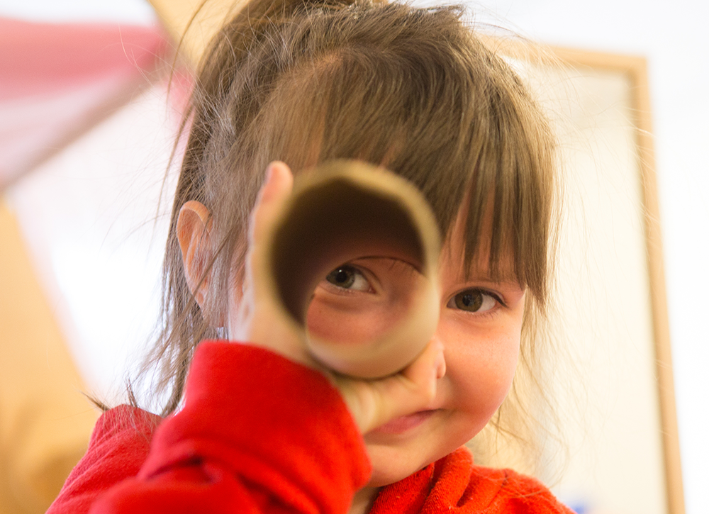 Girl playing with cardboard tubes
